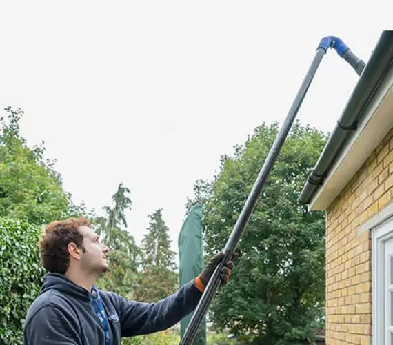 Man using pole to clean gutter- Bristol Pressure Washing