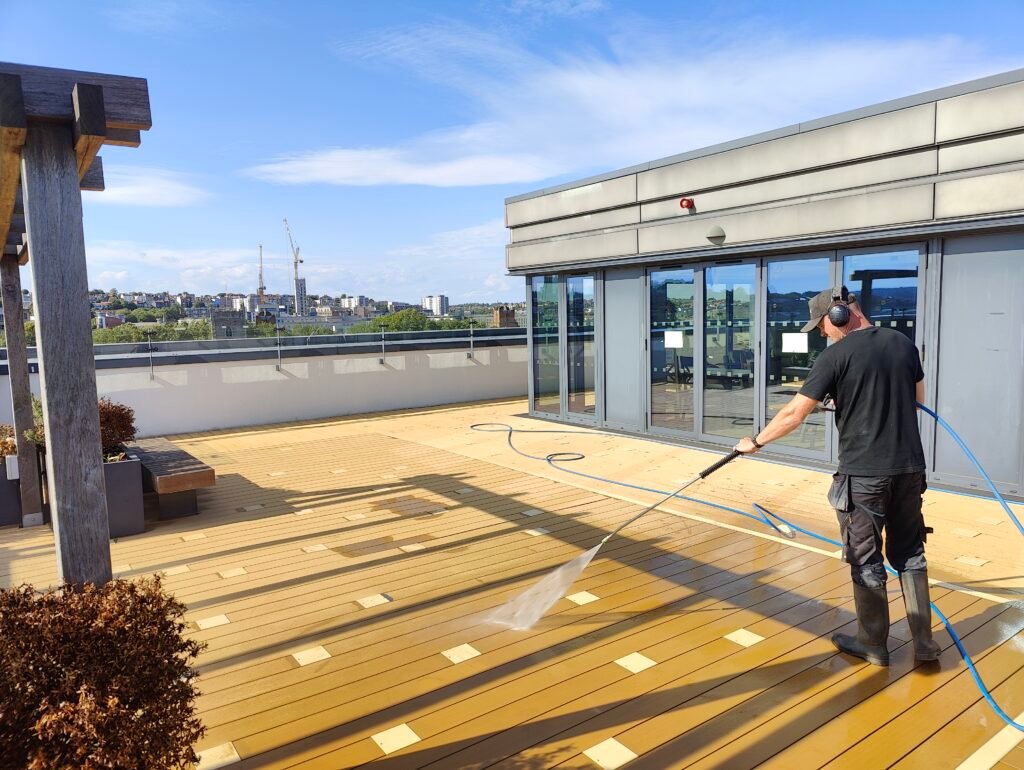 Operative pressure washing composite decking on a rooftop terrace in Bristol